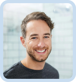 Smiling man with short brown hair and beard wearing a dark shirt against a light tiled background