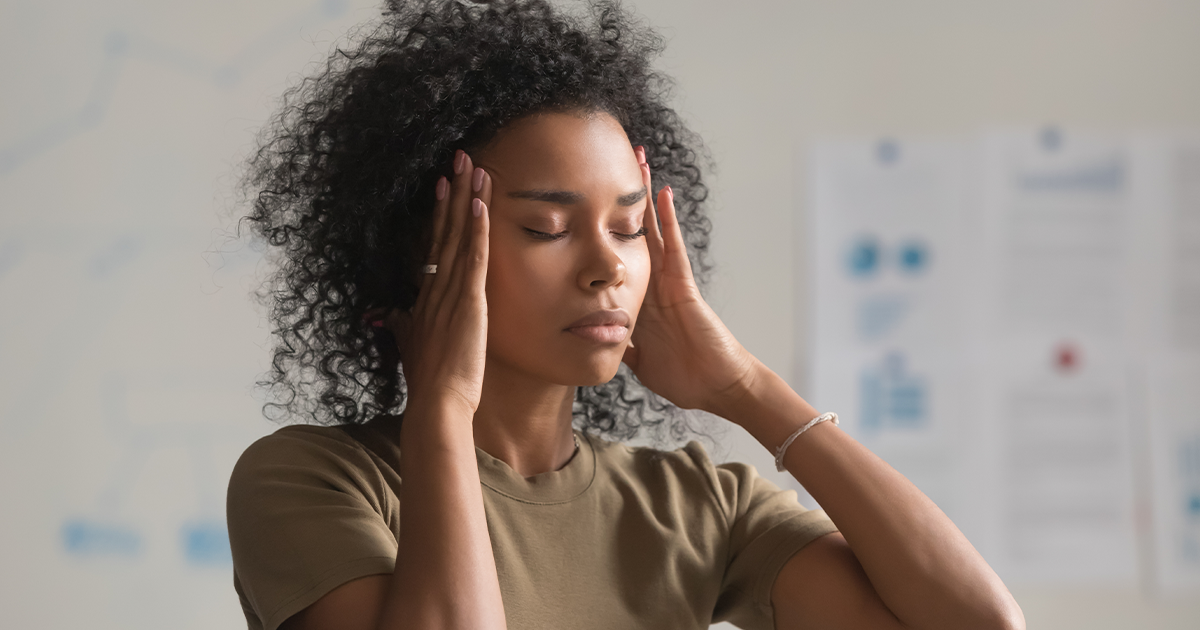 “Woman with closed eyes holding her temples, appearing stressed or overwhelmed