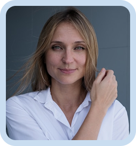 Woman with blonde hair wearing a white blouse smiling softly against a gray background