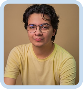 Smiling man with short dark hair and glasses wearing a yellow shirt against a beige background