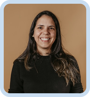 Smiling woman with long dark hair wearing a black sweater against a tan background