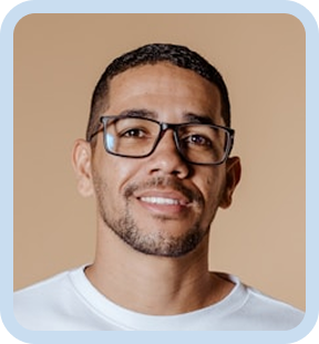 Smiling man wearing glasses and a white shirt standing in front of a neutral tan background