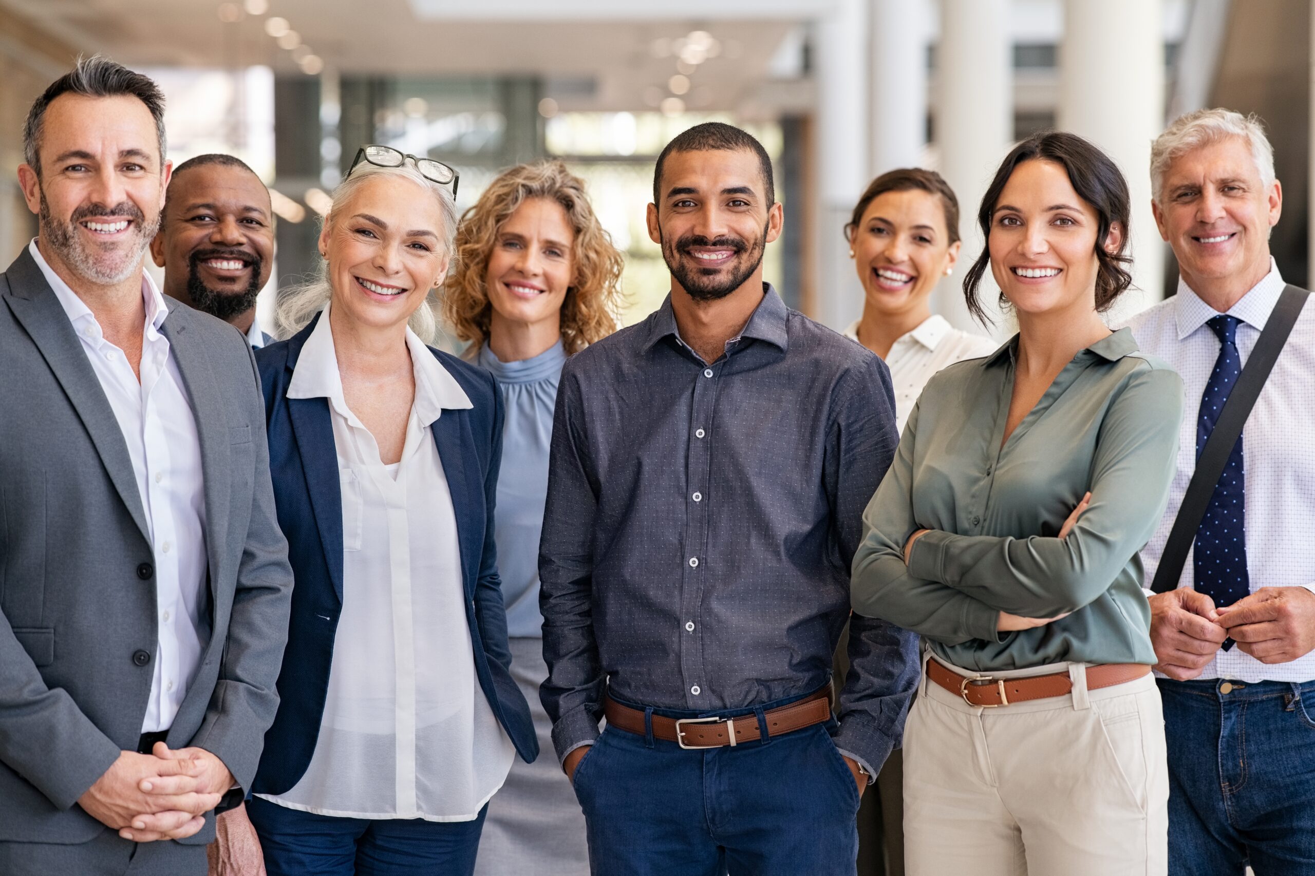Diverse team of professionals smiling and standing together in a modern office environment
