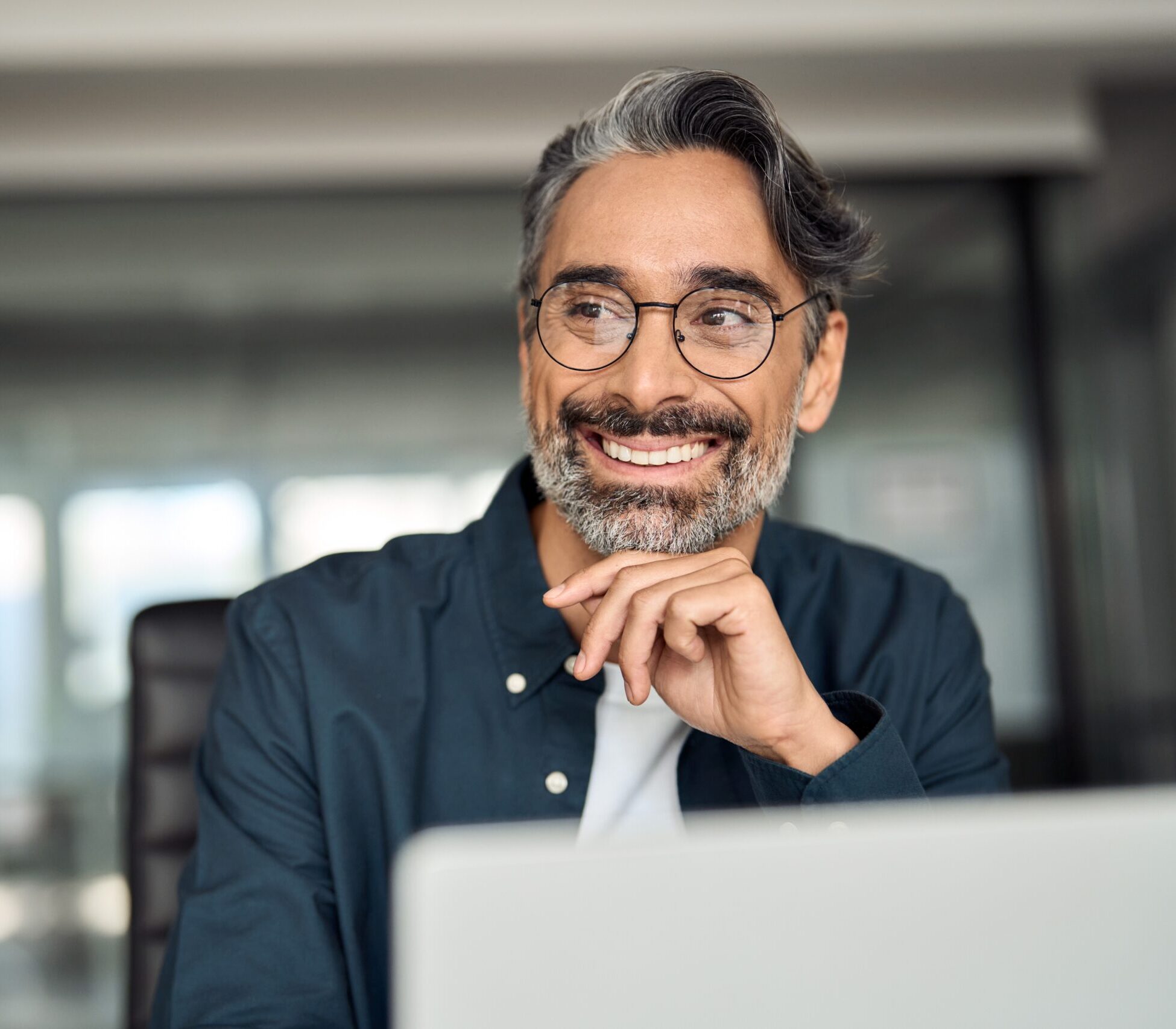 Smiling man with glasses looking to the side while sitting in an office environment