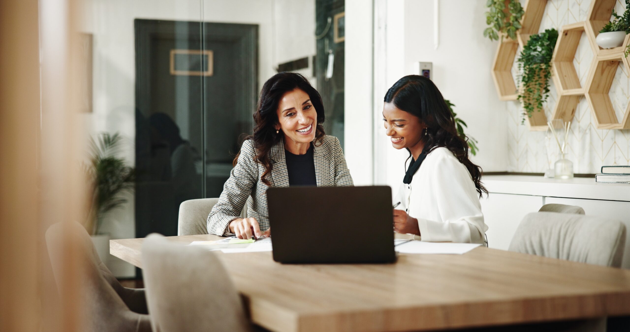 Two professionals smiling while collaborating on a project together in a modern office setting